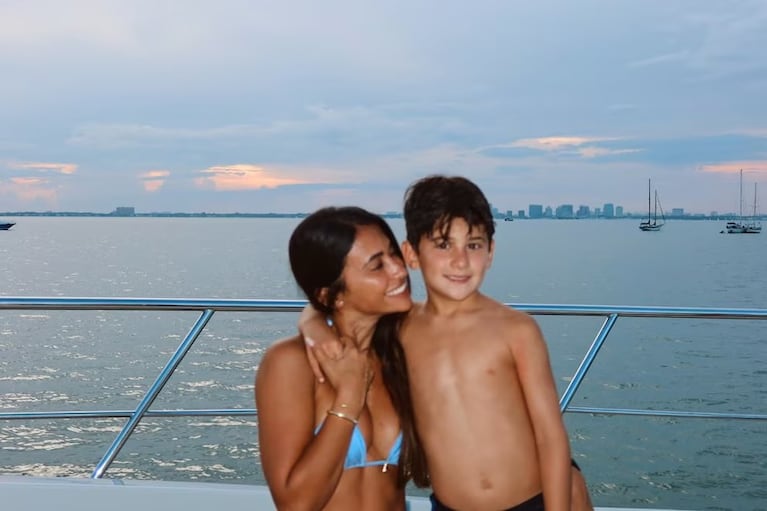 Antonela Roccuzzo abraza a su hijo Ciro en la cubierta de un yate, con el mar y la ciudad de fondo.
Crédito Instagram.