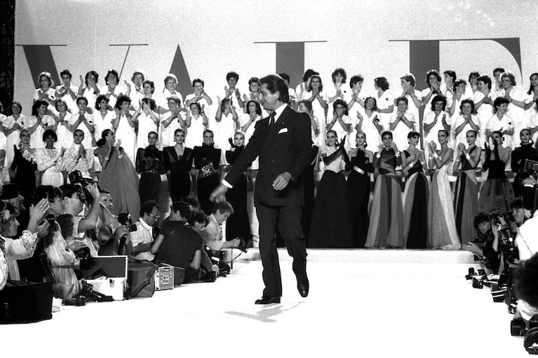 ARCHIVO - Modelos y colaboradores aplauden mientras Valentino Garavani saluda a los invitados que lo vitorean después de presentar su colección de Alta Costura Otoño-Invierno 1986-1987 el 25 de julio de 1986 en Roma. (Foto AP/Gianni Foggia, archivo)