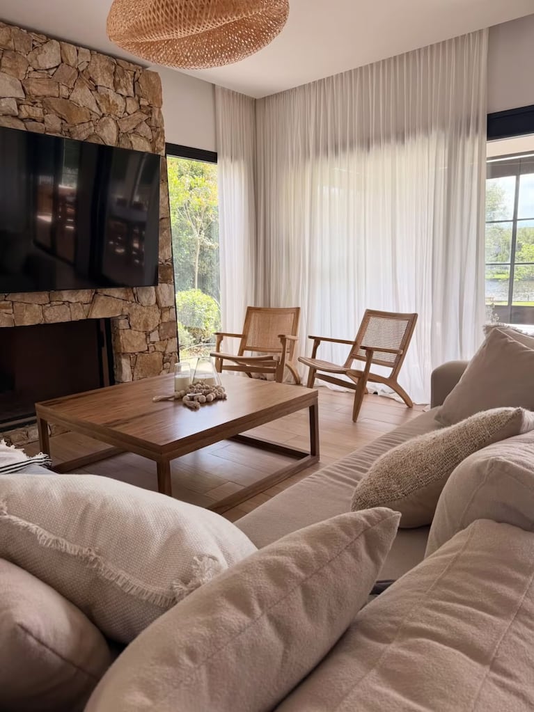El living de la nueva casa de Noelia Marzol y Ramiro Arias, con sillón en L, mesa ratona de madera y una escalera de líneas simples de fondo. Crédito: Instagram @noeliamarzolok