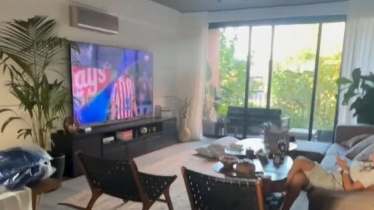 El living del departamento de Sofi Martínez, con pantalla gigante, plantas y los ventanales que dejan entrar luz natural todo el día. Crédito Instagram