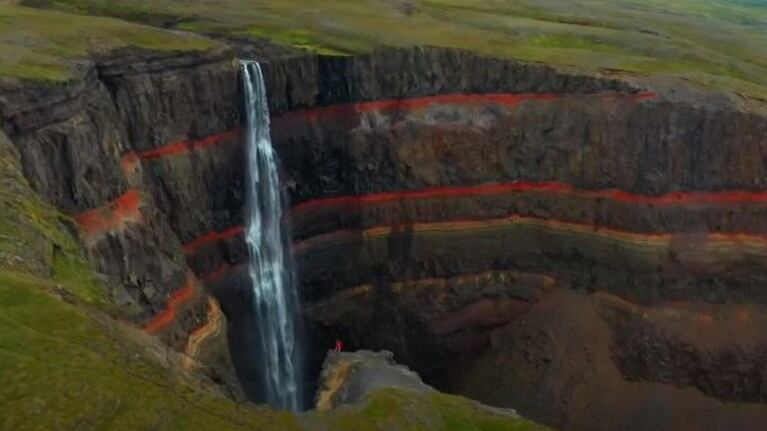 Espectaculares imágenes de una cascada rodeada de roca volcánica negra y roja