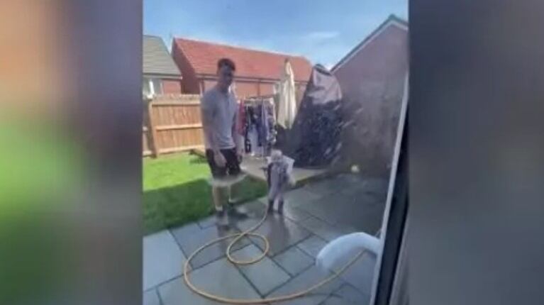 Este adorable niño ayudaba a su padre a limpiar el jardín hasta que perdió el control de la manguera