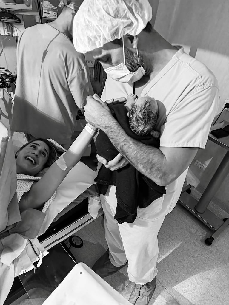 Facundo Miguelena sostiene a Serena en brazos vestido con ambo de quirófano, mientras Julieta Puente lo mira sonriente desde la camilla. Fuente: Instagram @julieta_puente.