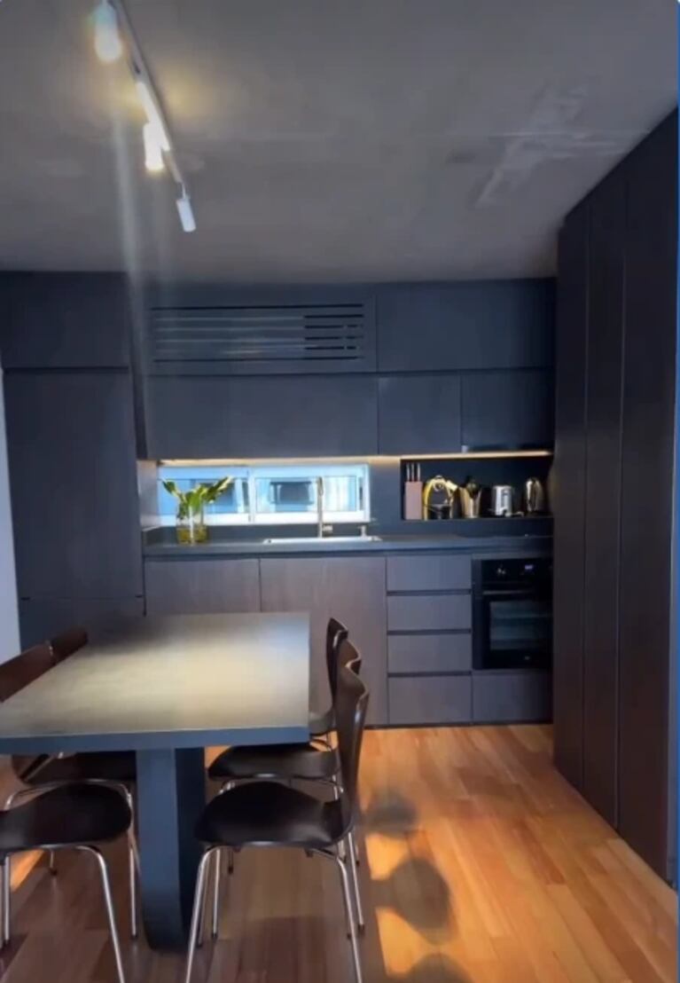 La cocina del departamento, con muebles en madera oscura y mesada integrada al comedor. Fuente: Instagram.