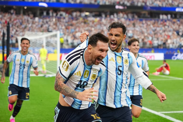 Leandro Paredes (5) agarra de la camiseta a su compañero Lionel Messi al celebrar el segund gol de Argentina en la victoria 2-0 ante Austria en el Grupo J del Mundial, el lunes 22 de junio de 2026, en Arlington, Texas. (AP Foto/Julio Cortez)