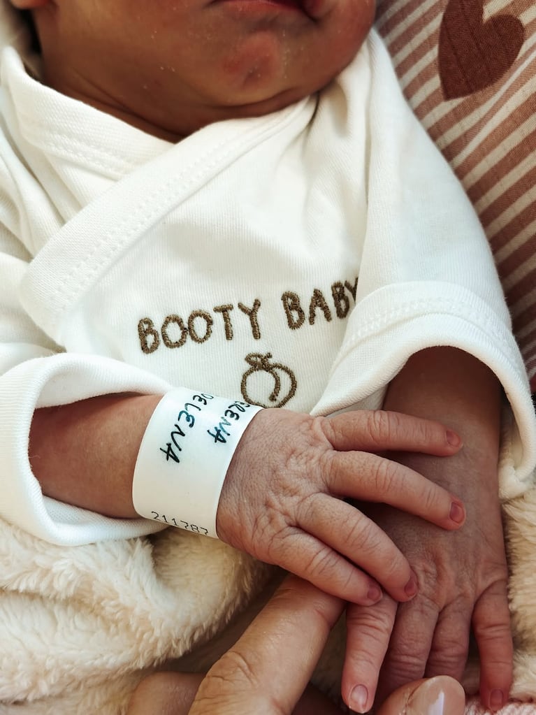 Primer plano de la mano de Serena, con la pulsera identificatoria del sanatorio, apoyada sobre la mano de uno de sus papás. Fuente: Instagram @julieta_puente.