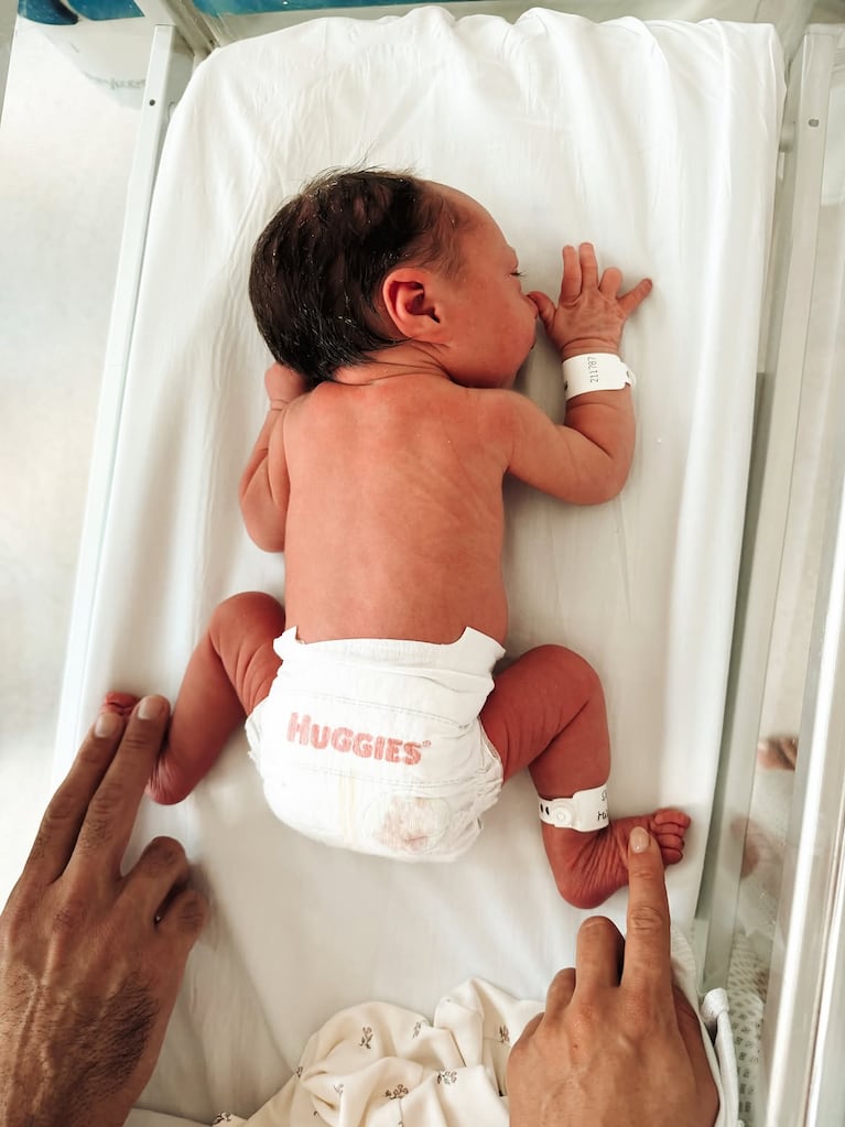 Serena recién nacida con las manos de sus papás acompañándola desde los costados. Fuente: Instagram @julieta_puente.