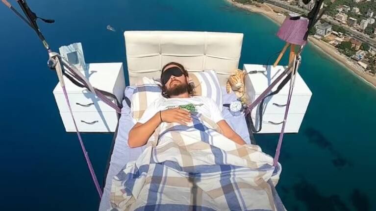 Un hombre vuela en parapente y acostado en una cama