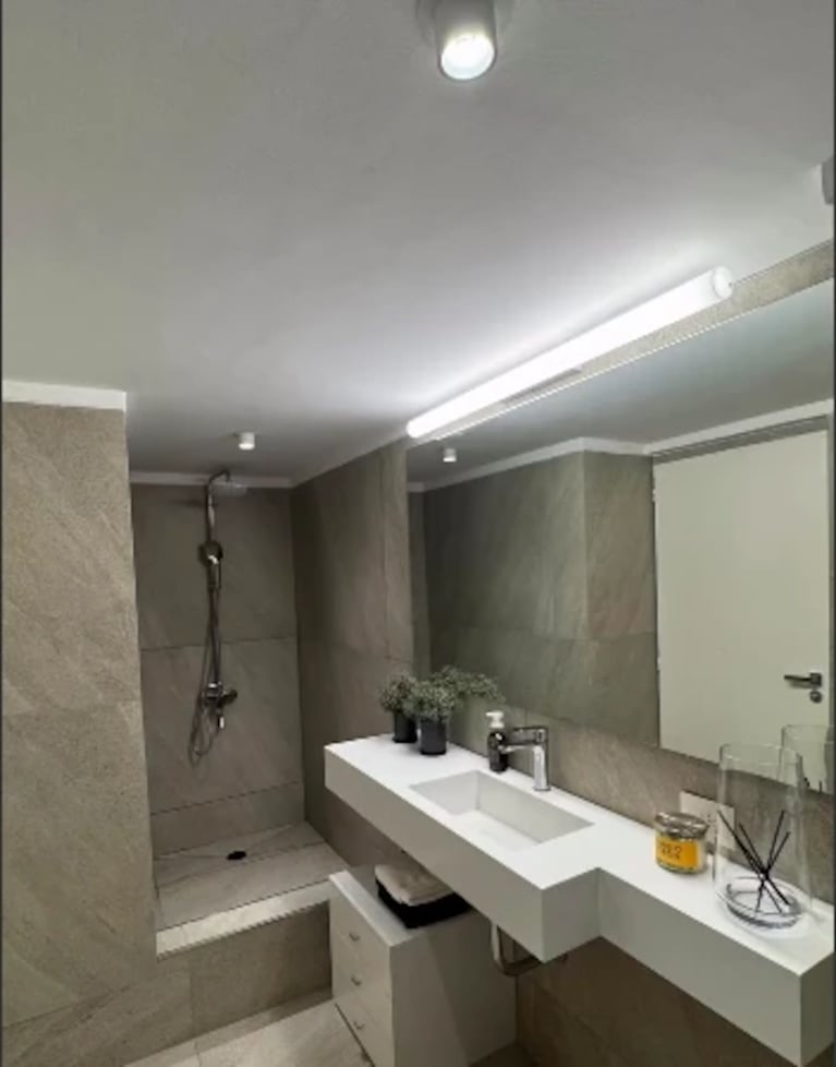 Uno de los baños de la vivienda, con revestimientos en tonos grises y bacha suspendida. Fuente: Instagram.